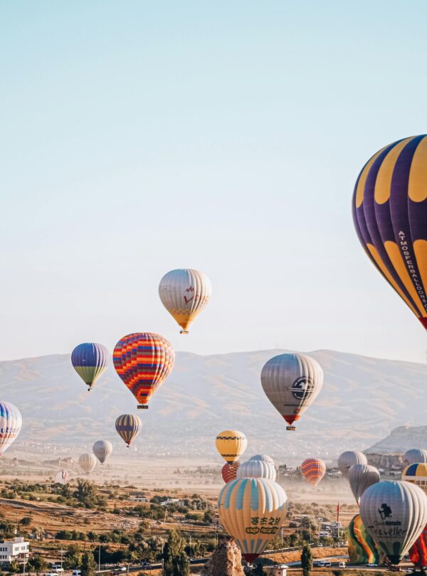 A scenic view of hot air balloons floating over Cappadocia, Türkiye at sunrise.